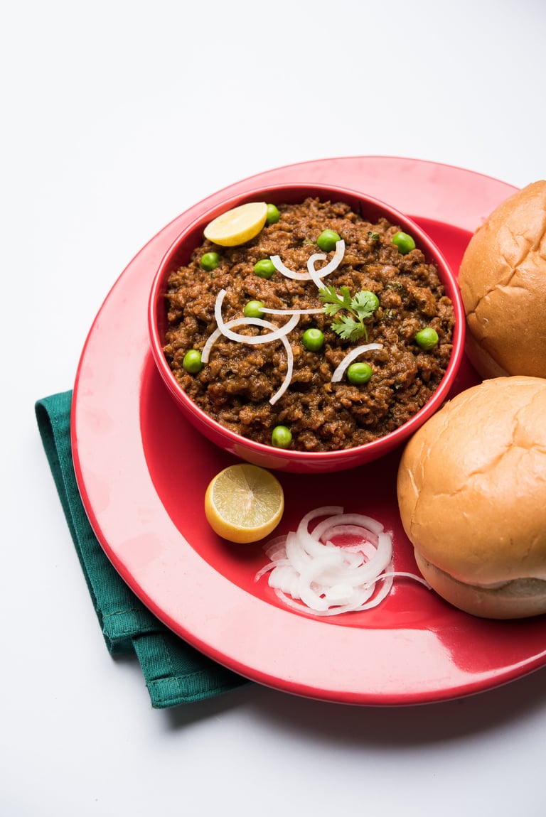 Indian Masala Kheema Pav or khima or Dry Spicy Minced Meat usually served with indian flat bread called kulcha/roti/chapati, garnished with green peas. Selective focus