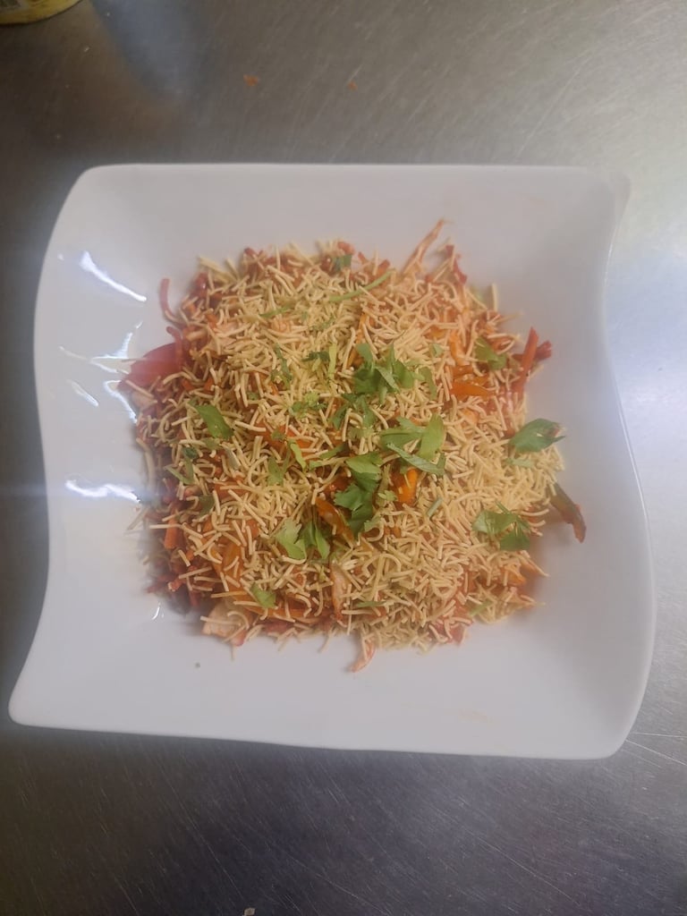 Crispy chow mein noodles with fresh green herbs on a white square plate