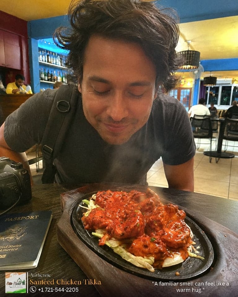 Man leaning over a plate of sauteed chicken tikka at a restaurant table indoors
