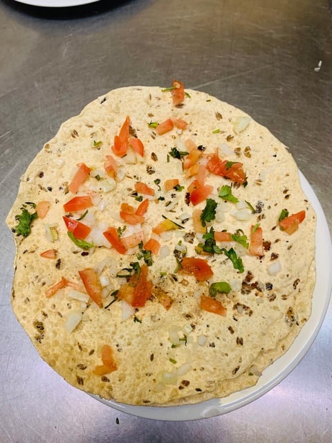 Flatbread topped with diced tomatoes, fresh cilantro, and spices on a white plate