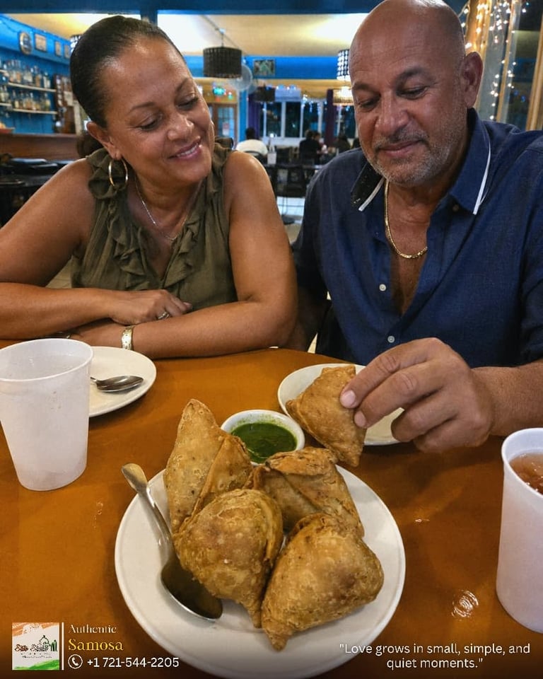 Two people enjoying samosa at a restaurant table with blue walls in the background