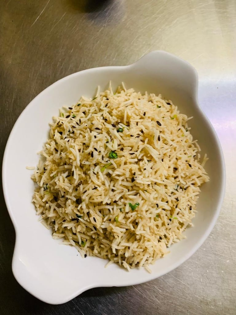 Cooked rice with herbs in a white decorative bowl on a wooden surface