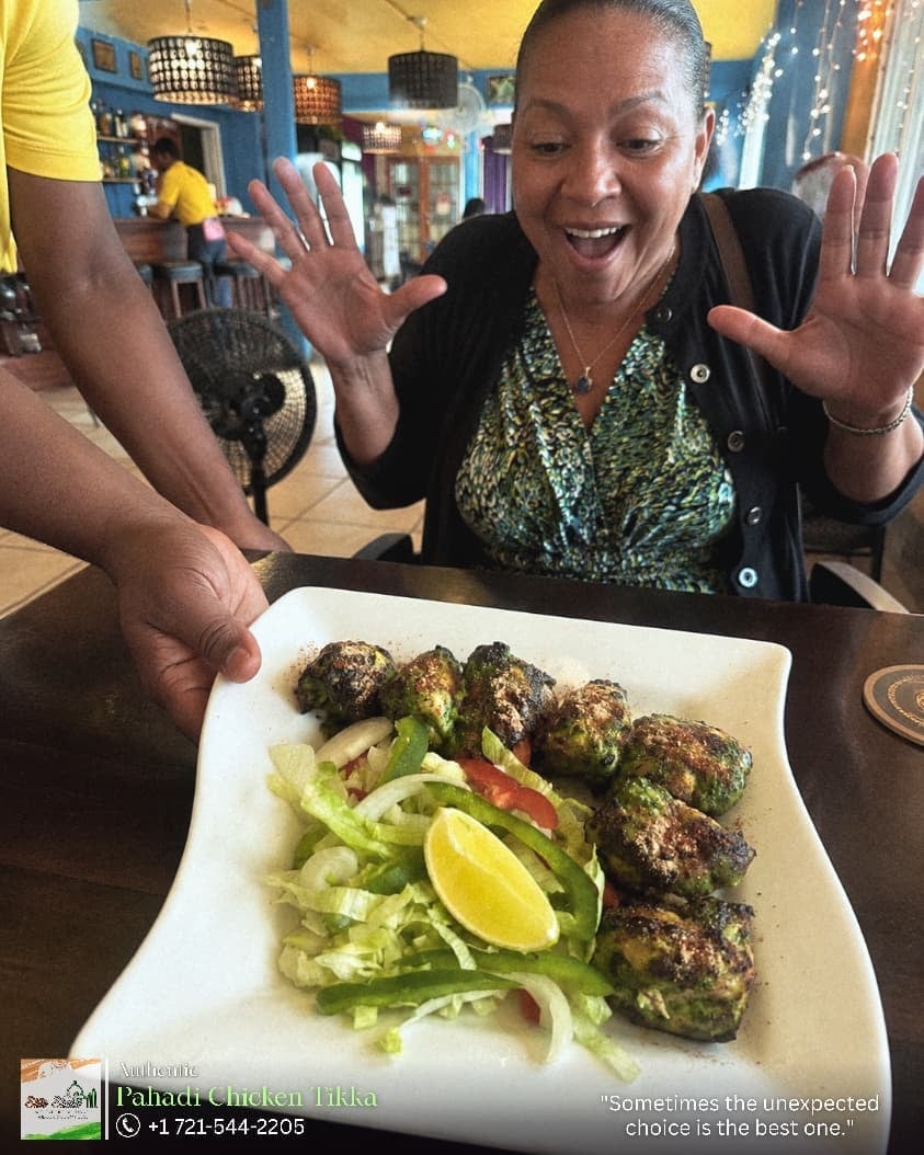 Woman smiling with hands raised in front of Tandoori Chicken Tikka dish at a restaurant